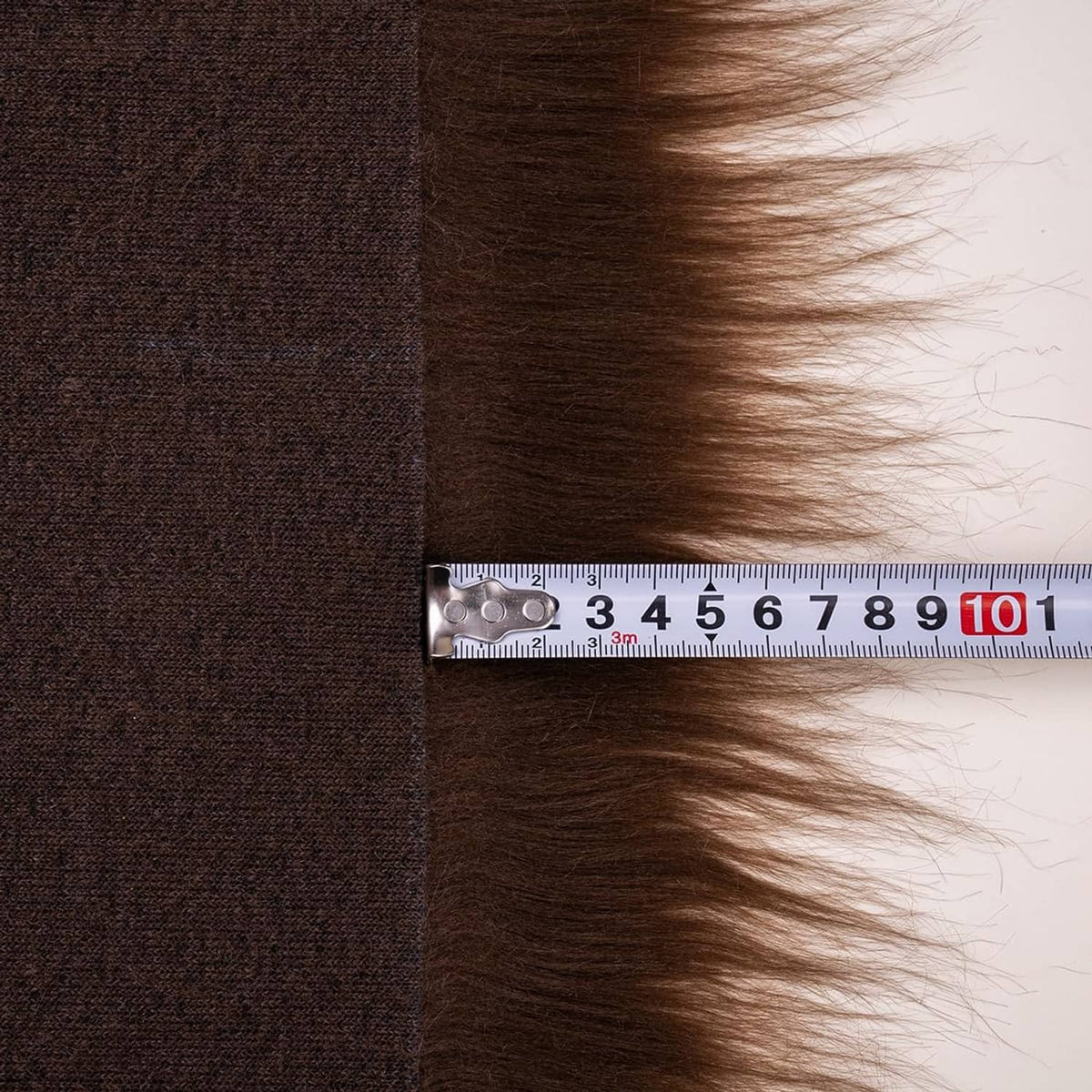 Brown faux fur fabric with backing cloth and a measuring tape along the edge.