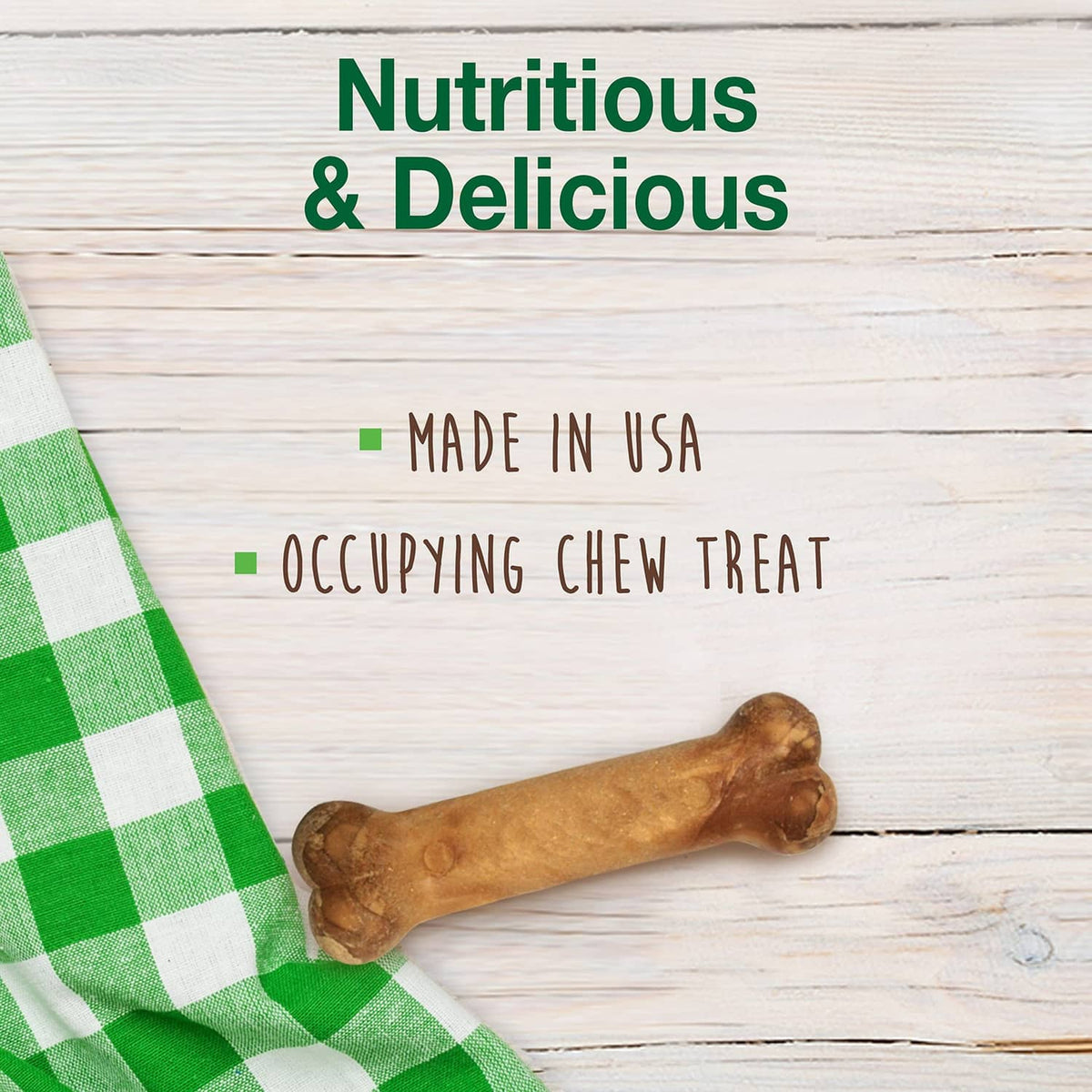 Single tan dog chew bone treat on a green-and-white cloth