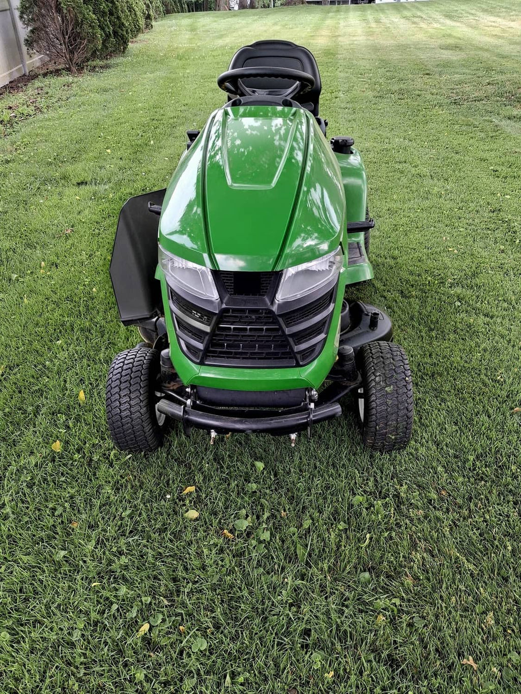 Green front hood and grille on a lawn tractor with black bumper and headlight openings