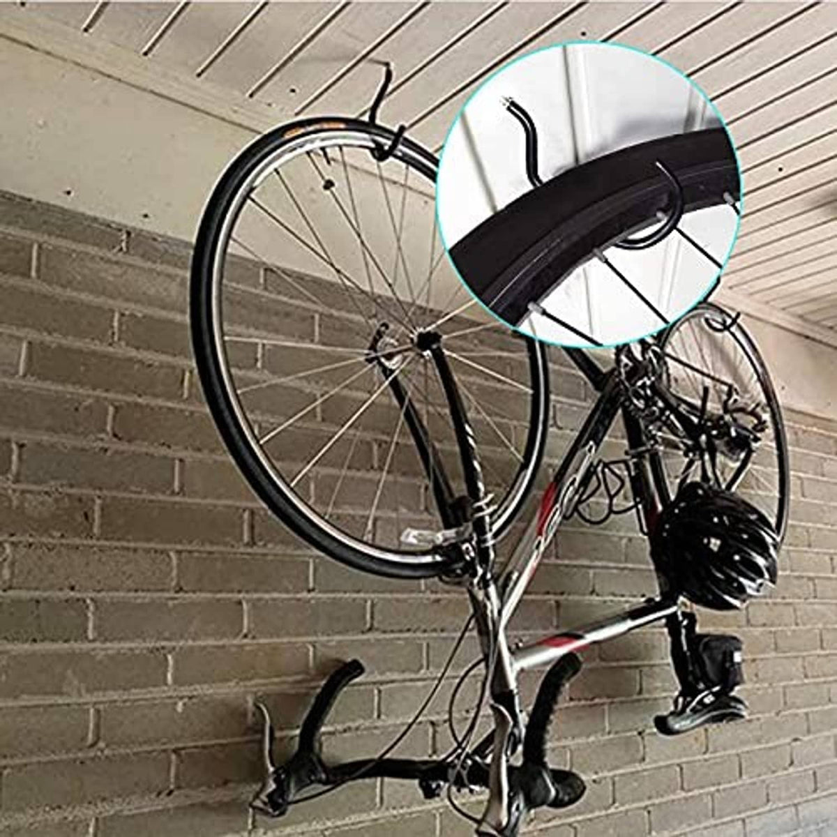 Black bicycle wall hook holding a bike by the front wheel on a brick wall