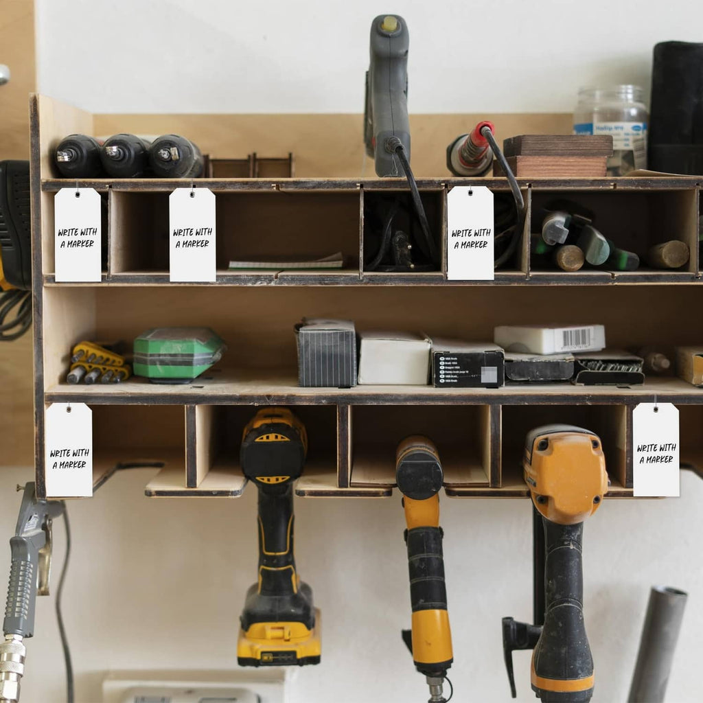 White plastic shipping tags hanging from tools and shelving using metal loops
