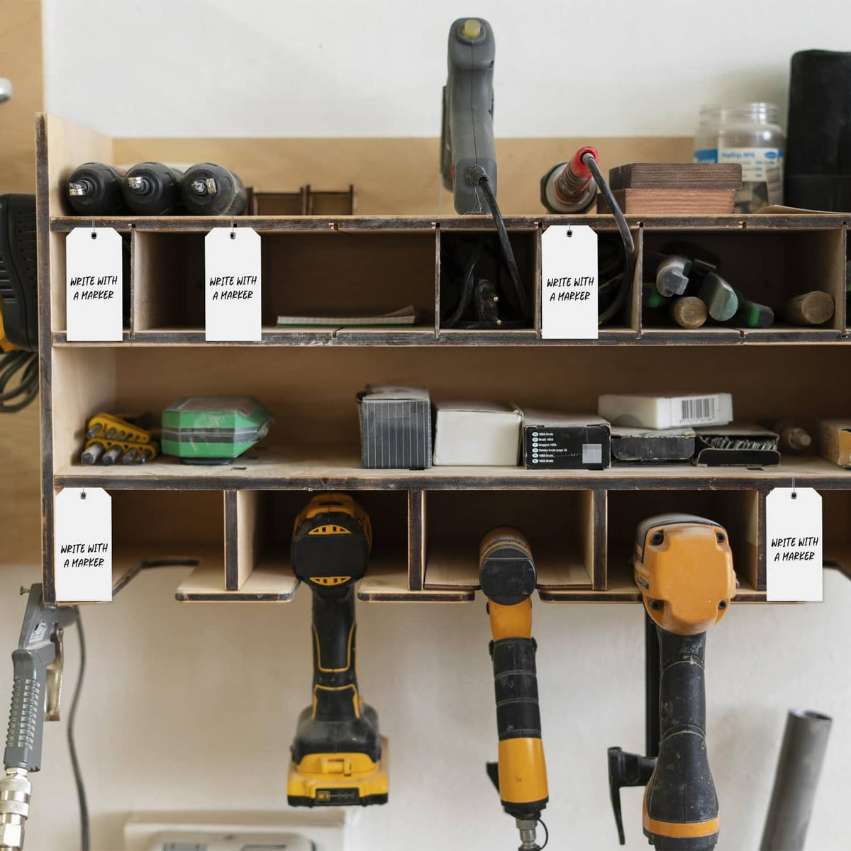 White plastic shipping tags hanging from tools and shelving using metal loops