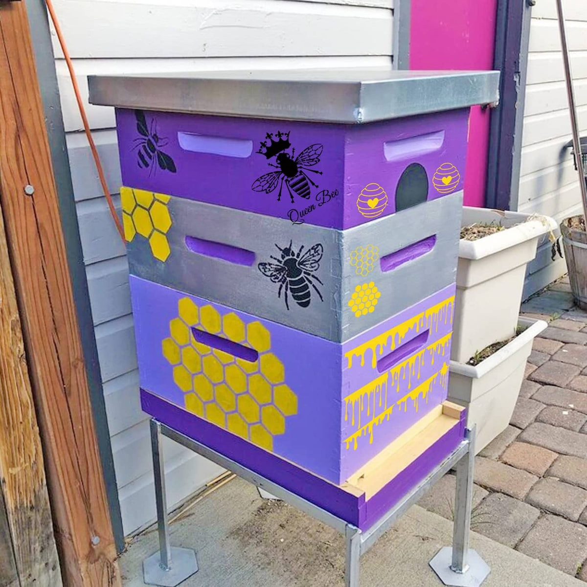 Bee-themed wooden beehive box painted purple with honeycomb and bee stencil designs