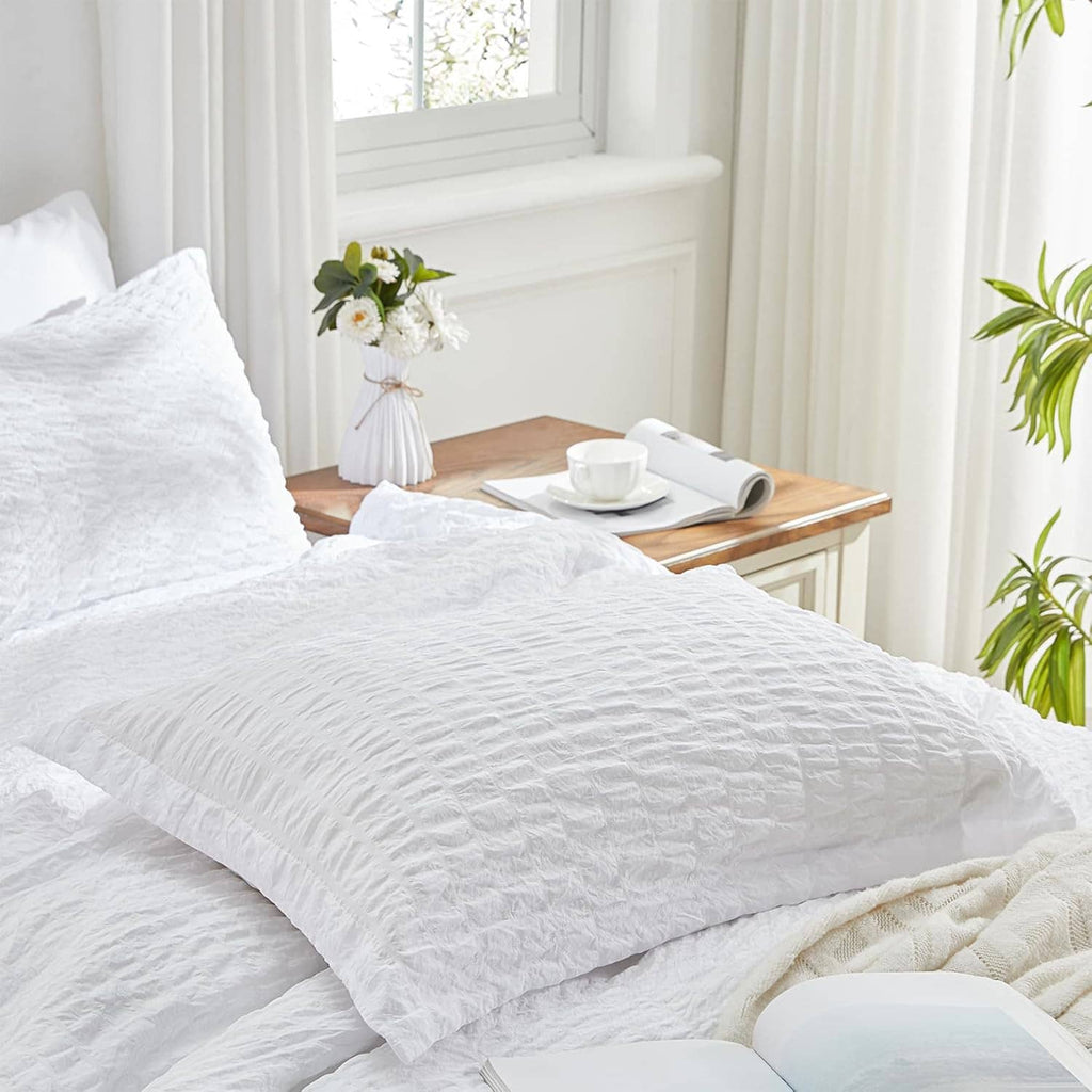 White king seersucker comforter and pillow shams with tasseled beige throw on the bed