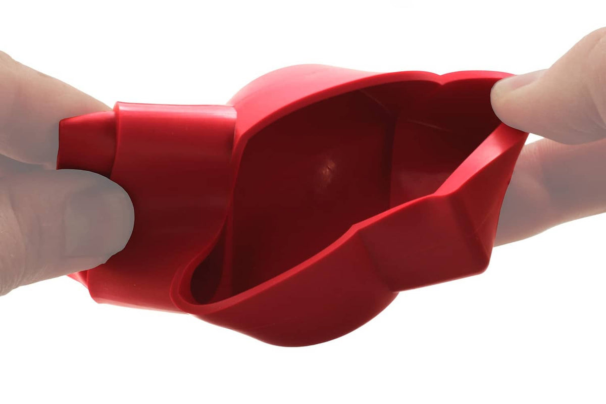 Red battery terminal cover held in hand, showing interior metal contact area