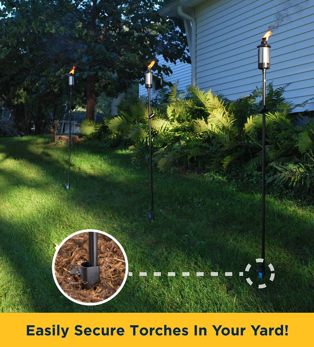 Four black metal torch stakes planted in the yard for upright torches