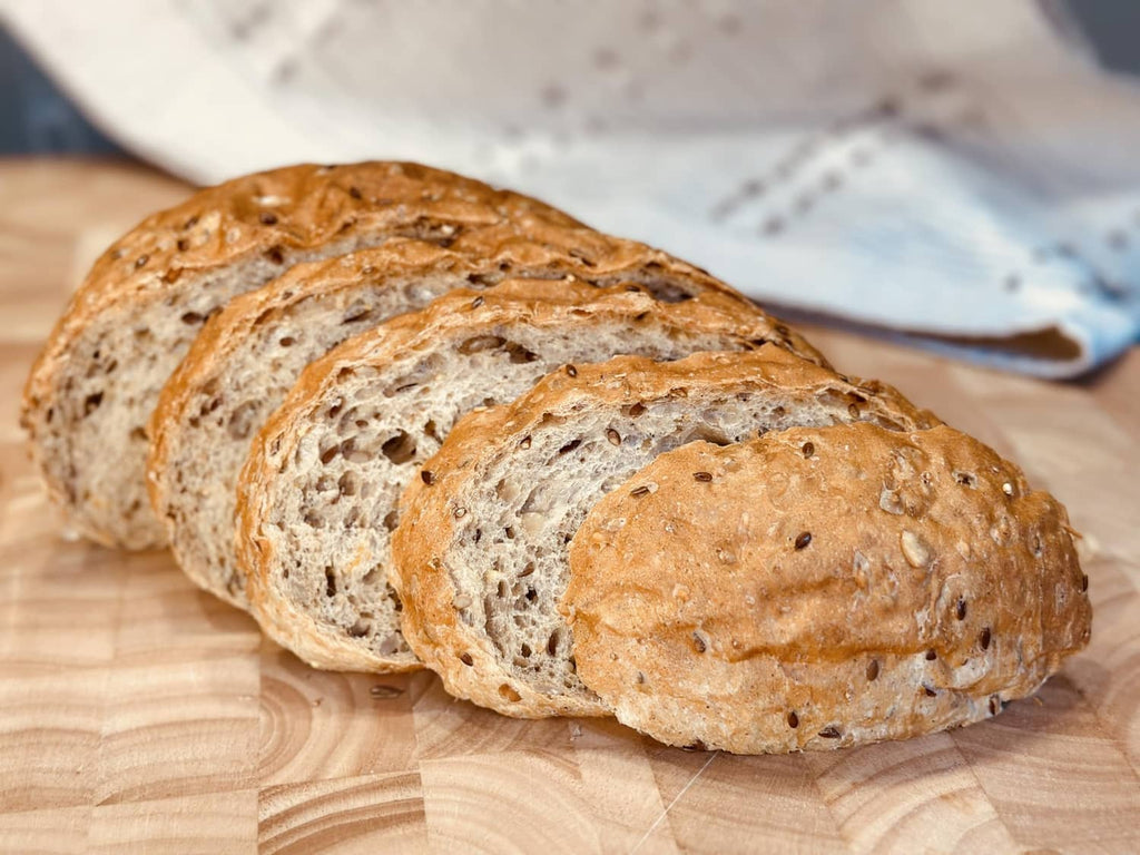 Sliced-style 8 grain bread loaf pieces with seeded crust on a wooden board