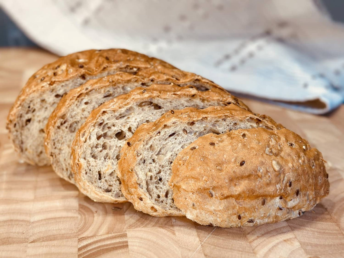 Sliced-style 8 grain bread loaf pieces with seeded crust on a wooden board