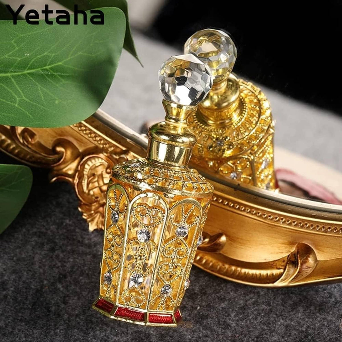 Golden ornate perfume bottle with crystal ball cap, rhinestone insets, red base details