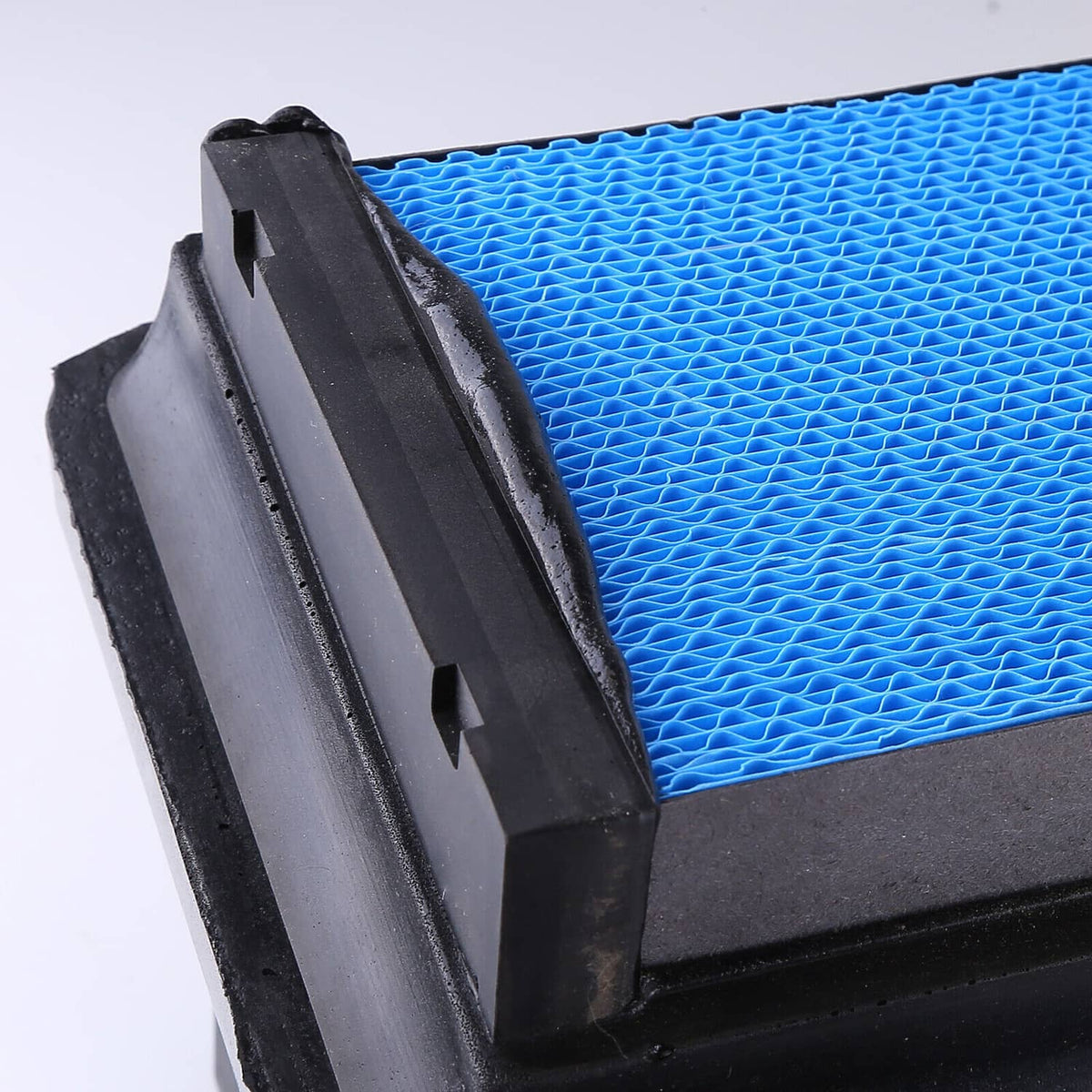 Engine air filter close-up showing black frame and blue pleated media