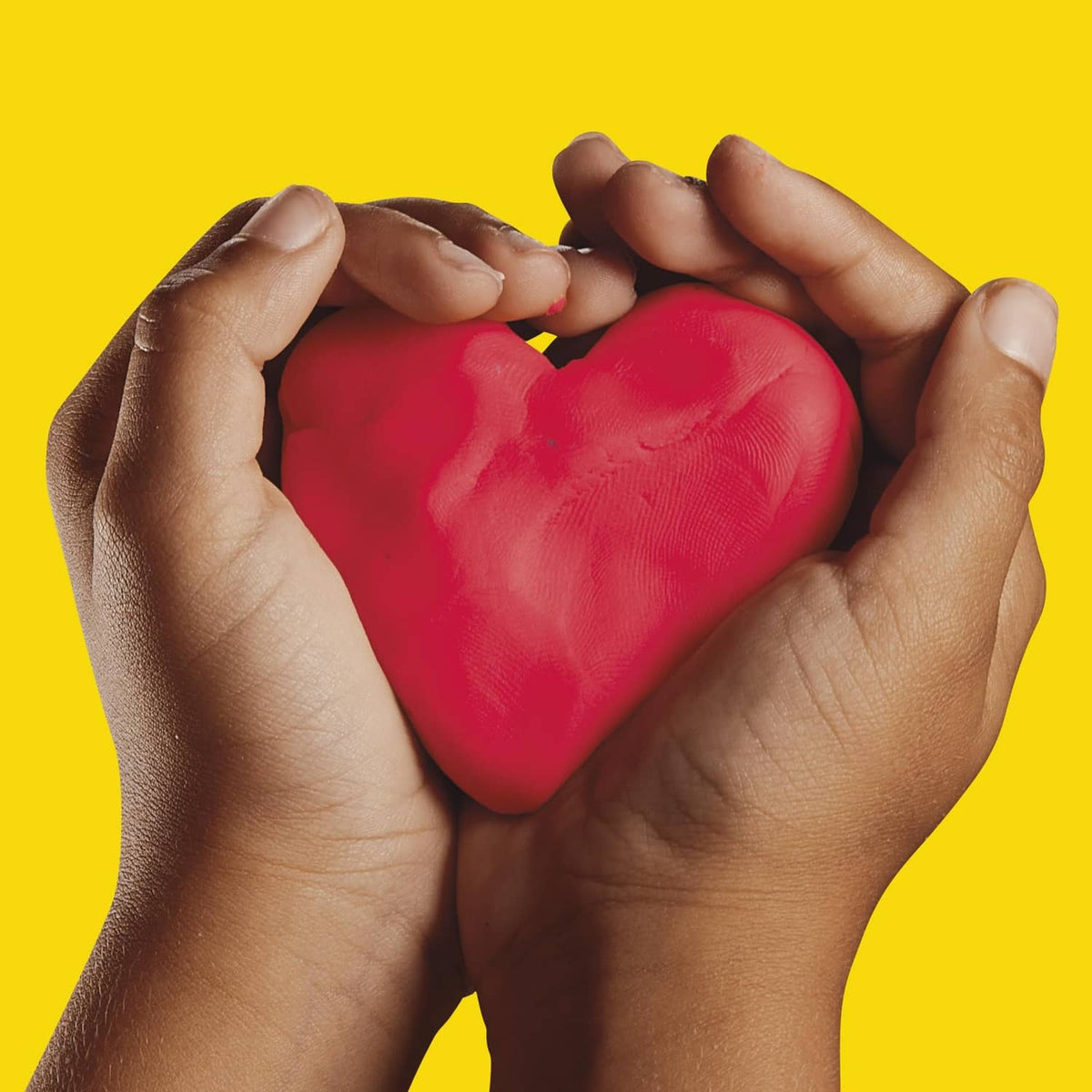 Hands forming a red heart shape with Play-Doh modeling clay