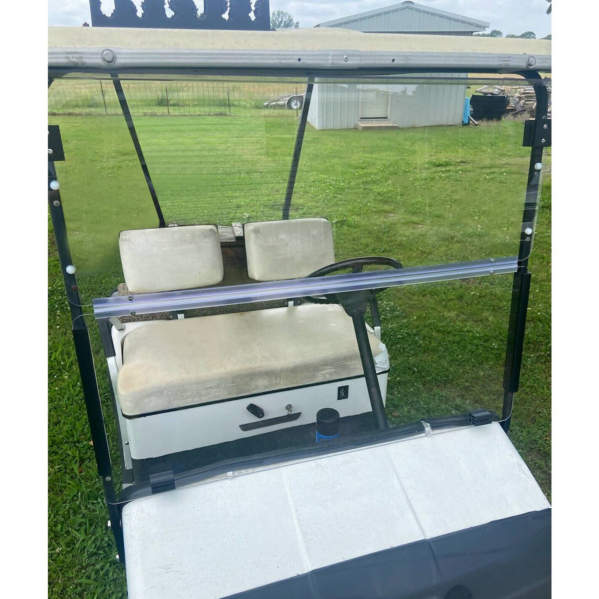 Installed clear golf cart windshield with black frame supports and blue tint bar