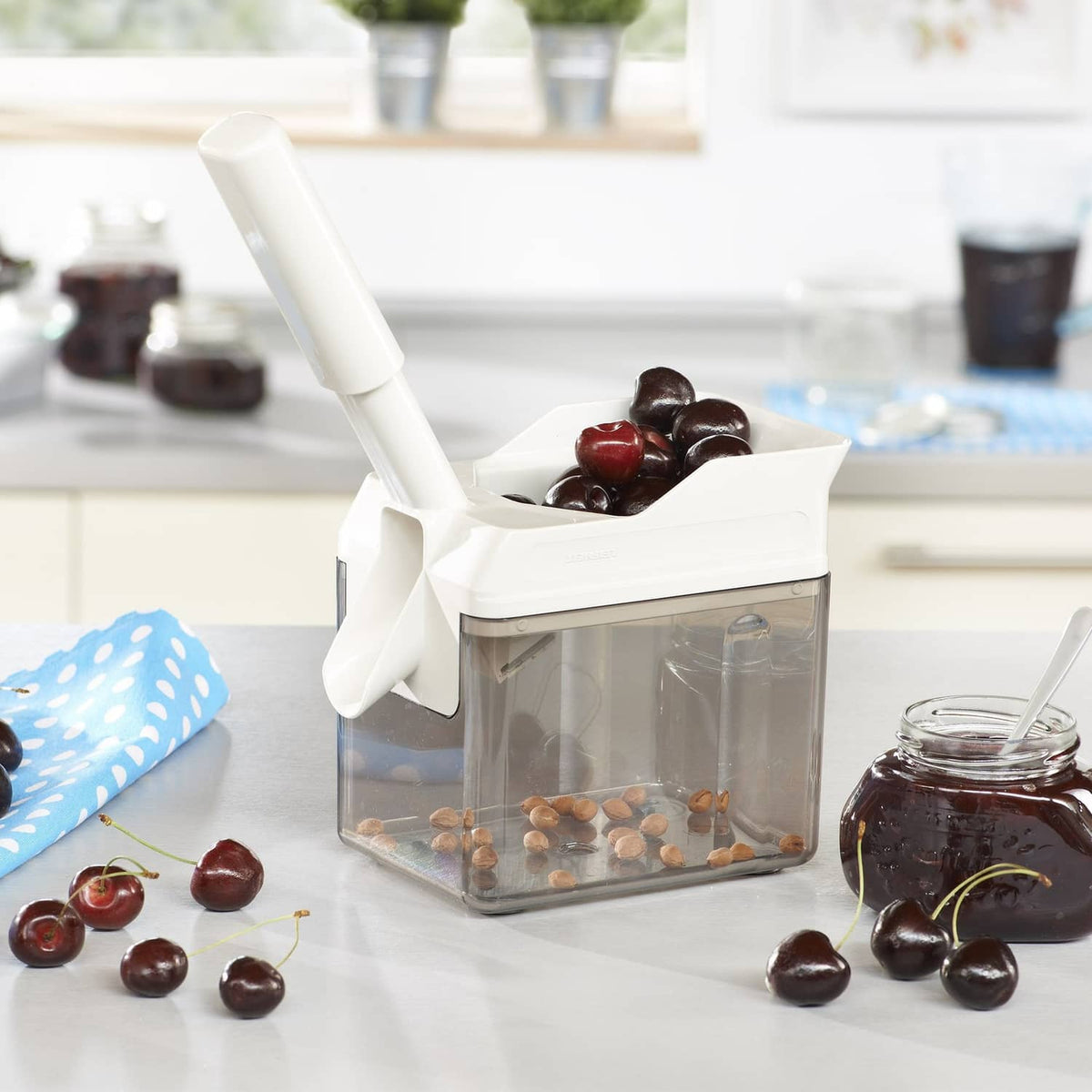 White Leifheit cherry stone remover releasing cherries into the clear collection bin