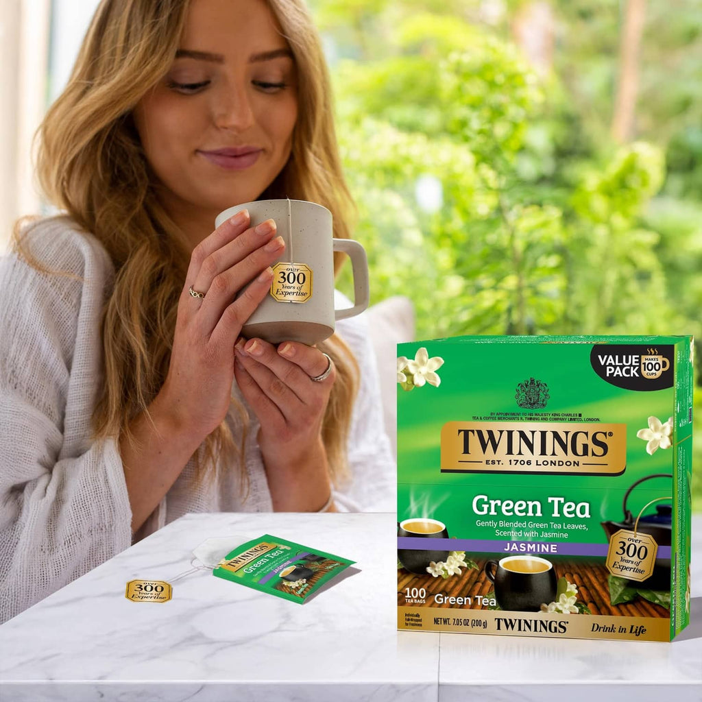Twinings Green Tea Jasmine tea pack with mug, tea bag wrappers, and jasmine flowers