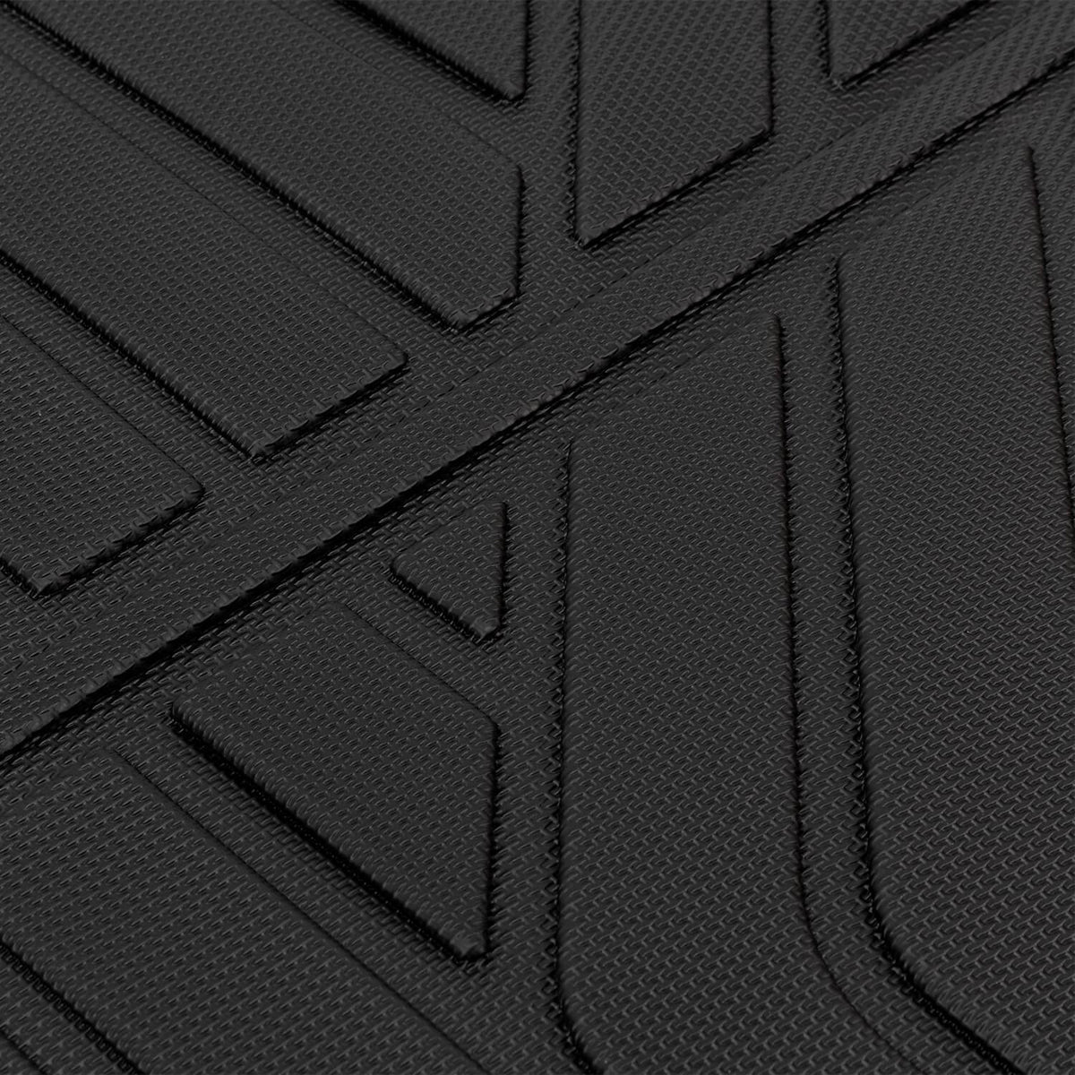 Black rubber floor mat surface with raised ridges and channels for traction, close-up