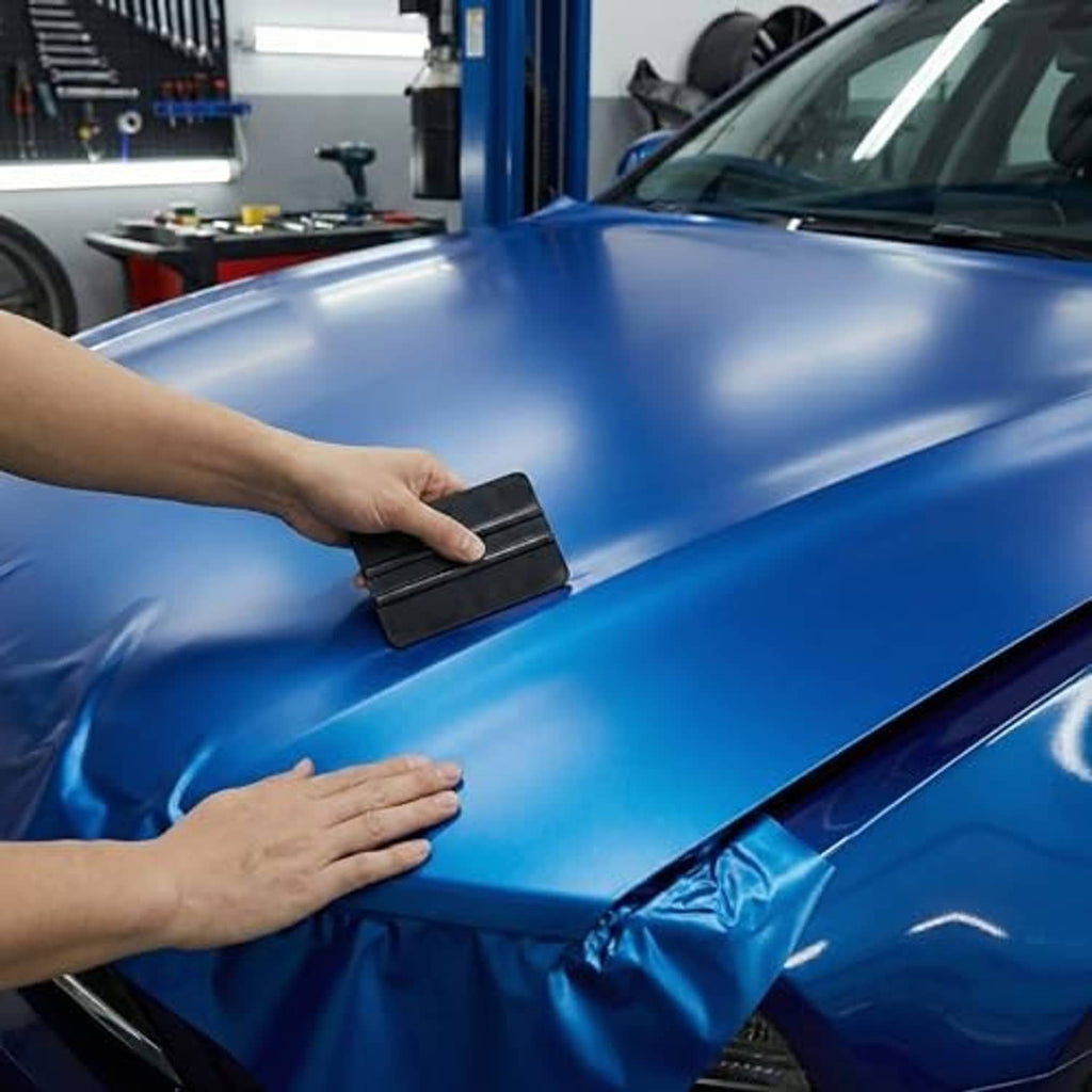 Black vinyl squeegee scraper smoothing a surface, rectangular ribbed plastic tool.