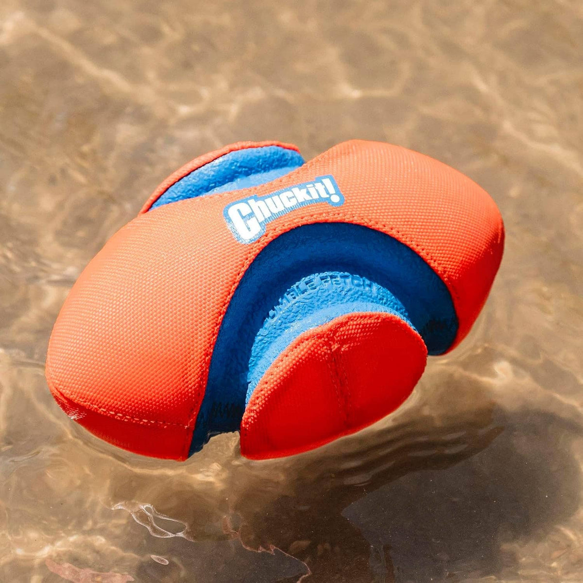 Orange and blue Chuckit! grooved dog football toy floating in water