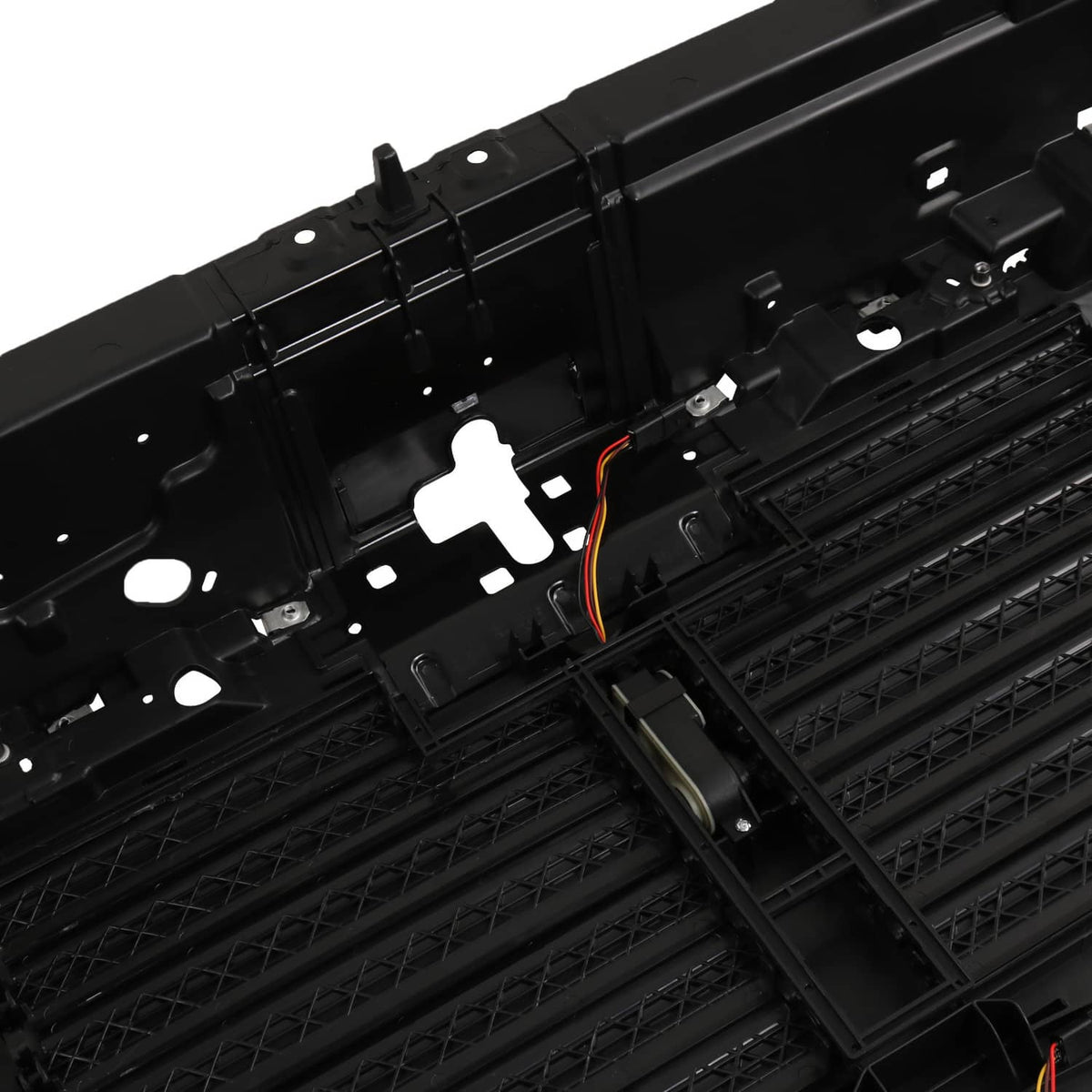 Black active grille shutter with actuator mount and visible orange wiring