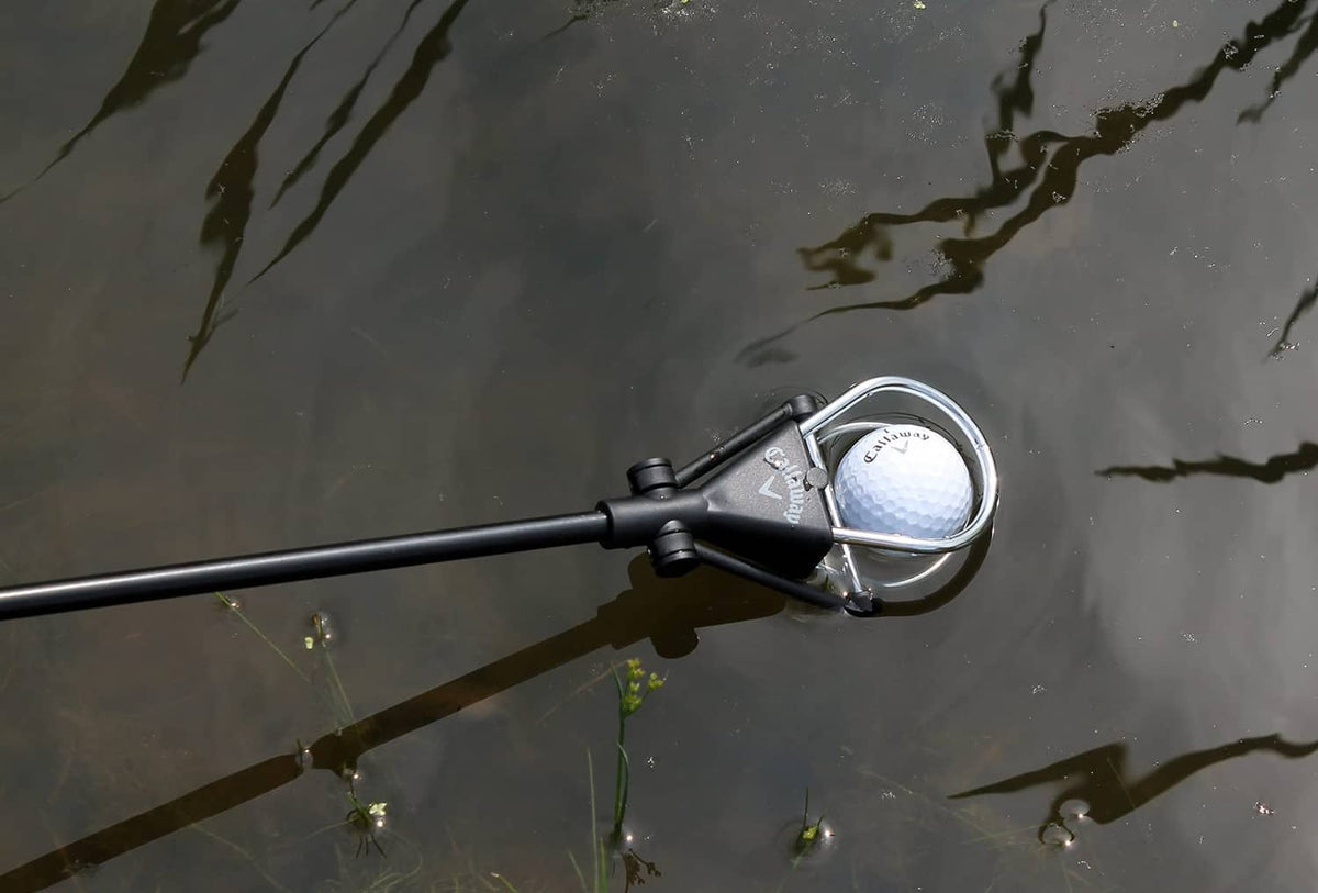 Ball retriever scoop over water holding a white golf ball
