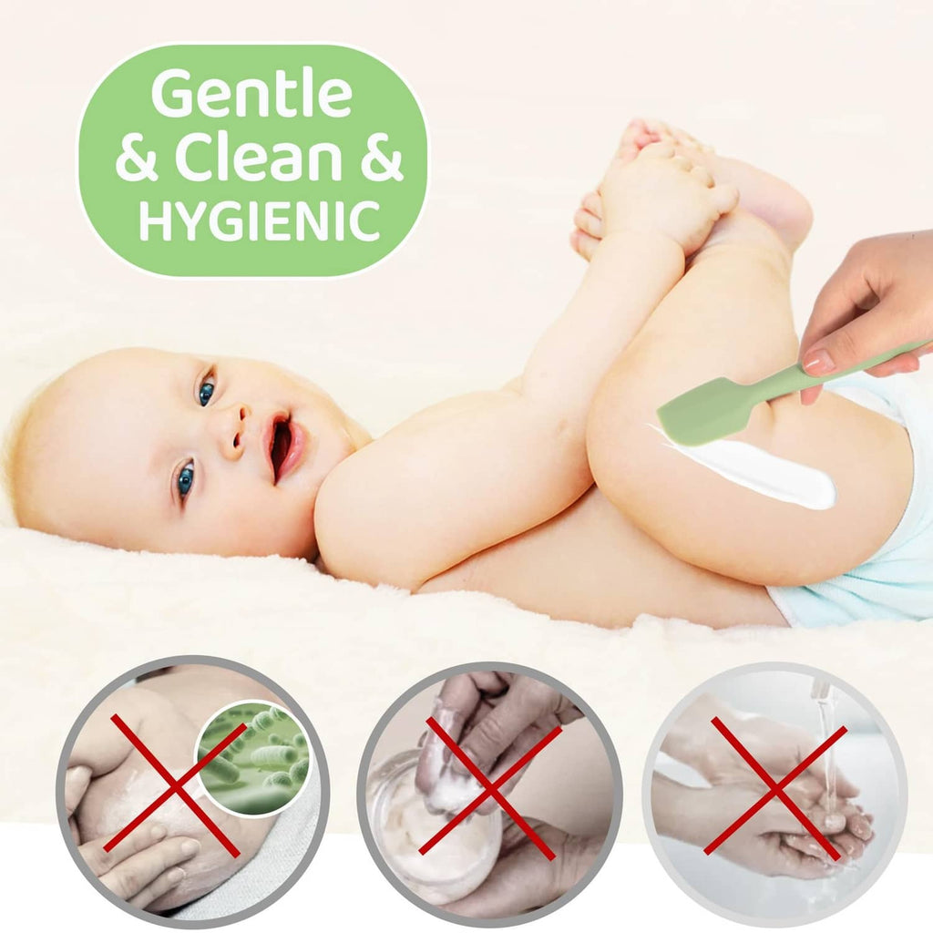 Baby on a changing pad with a green silicone diaper spatula and white scraper