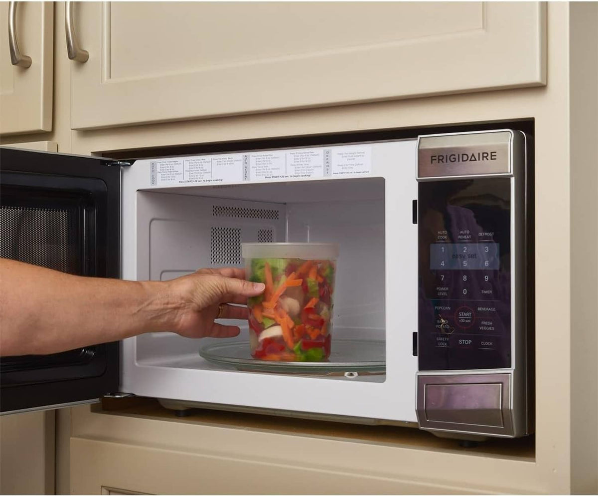Hand placing a clear deli food container into a microwave for reheating