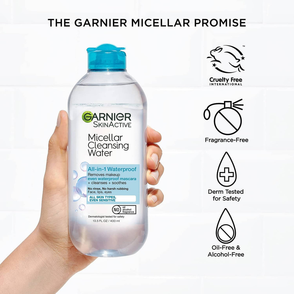 Hand holding Garnier SkinActive micellar cleansing water bottle with blue cap and icons.