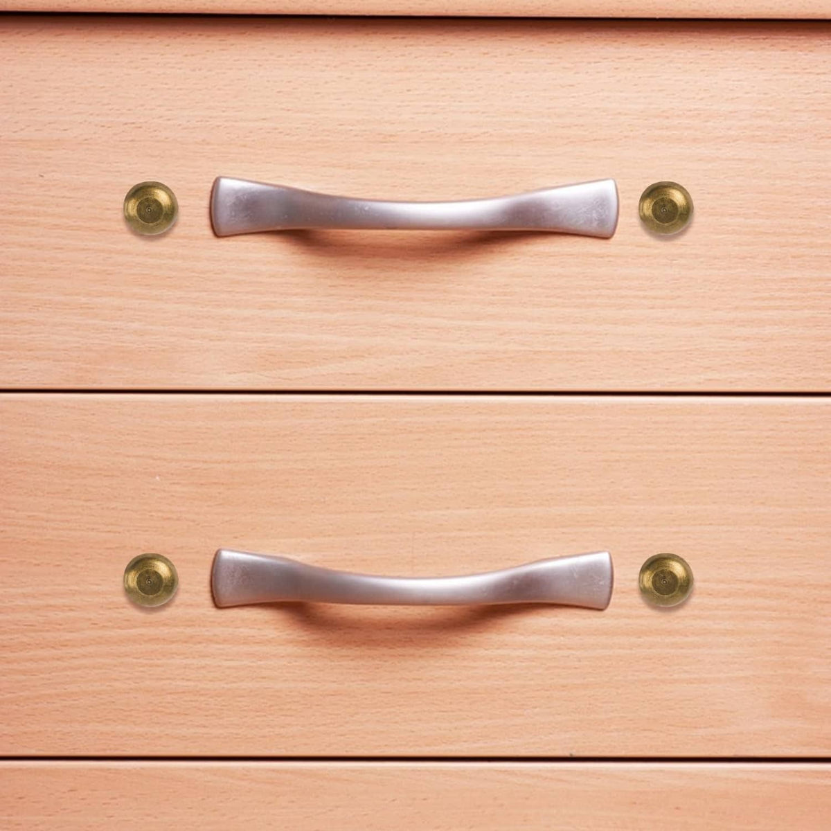 Bronze screw caps securing a cabinet handle on a wooden drawer front