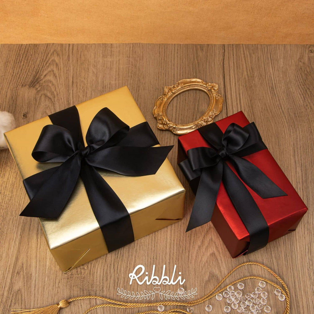 Black satin ribbon bows on gold and red wrapped gifts, with long ribbon ends