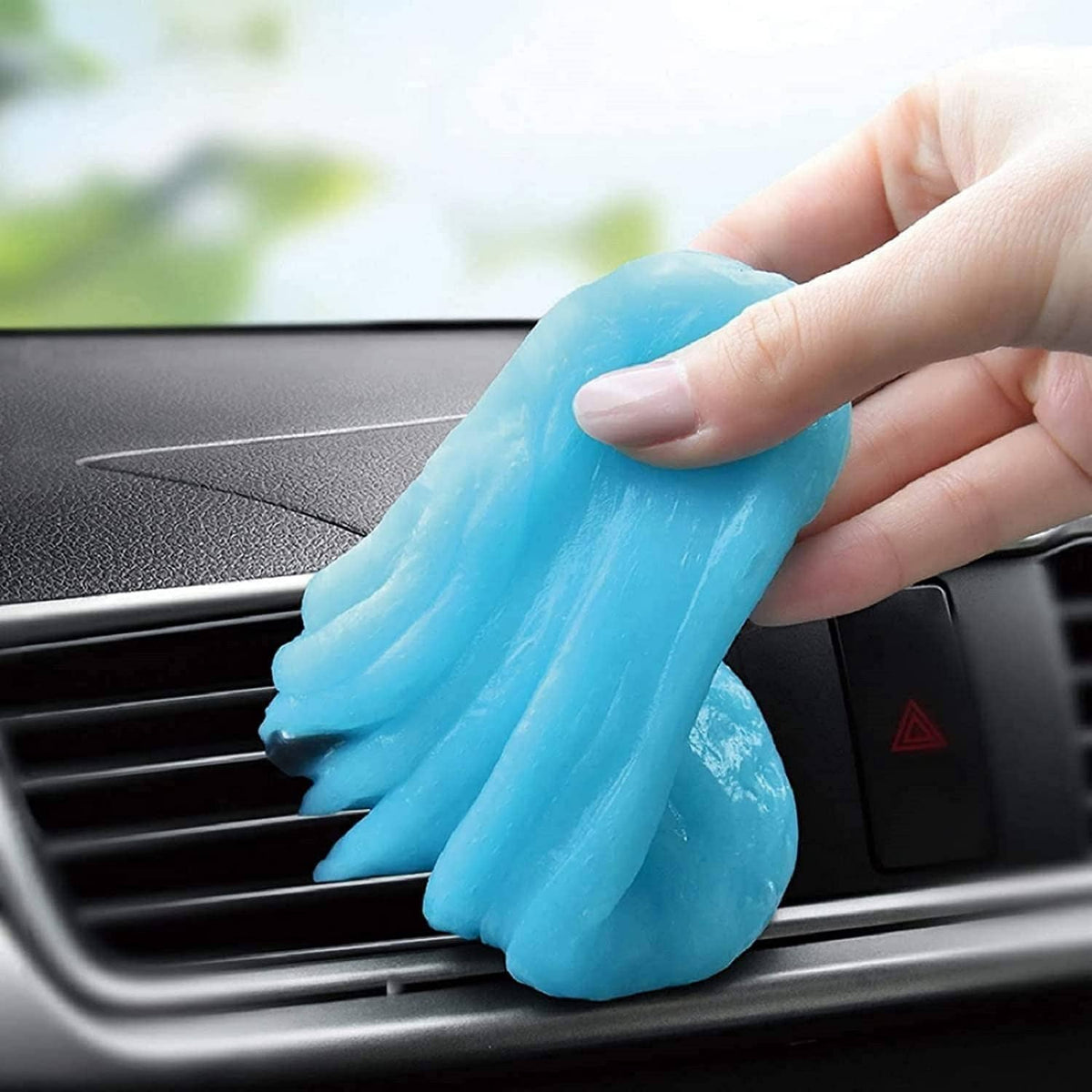 Blue cleaning gel putty held above car vent grille