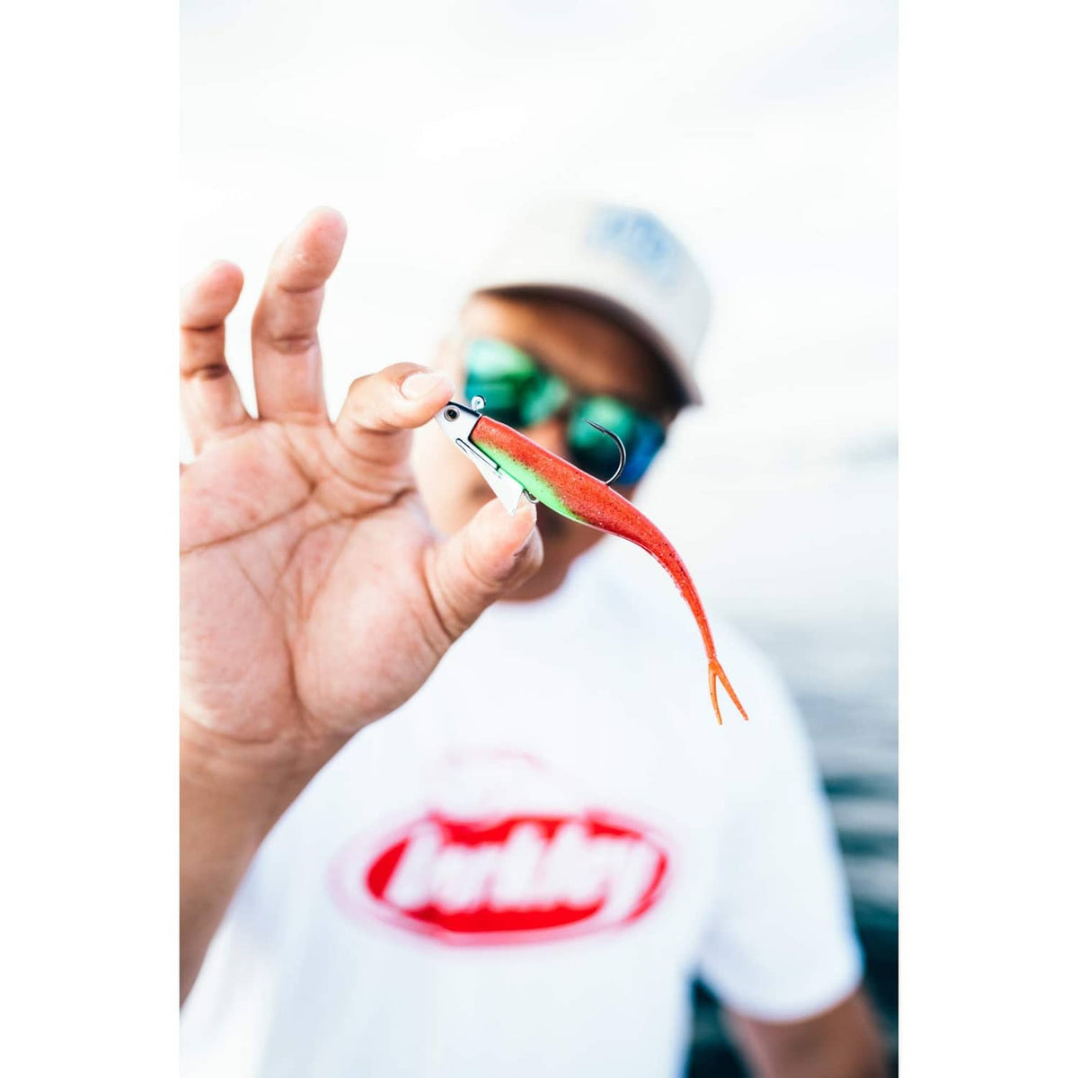 Red-green saltwater lure with hook held in an open hand