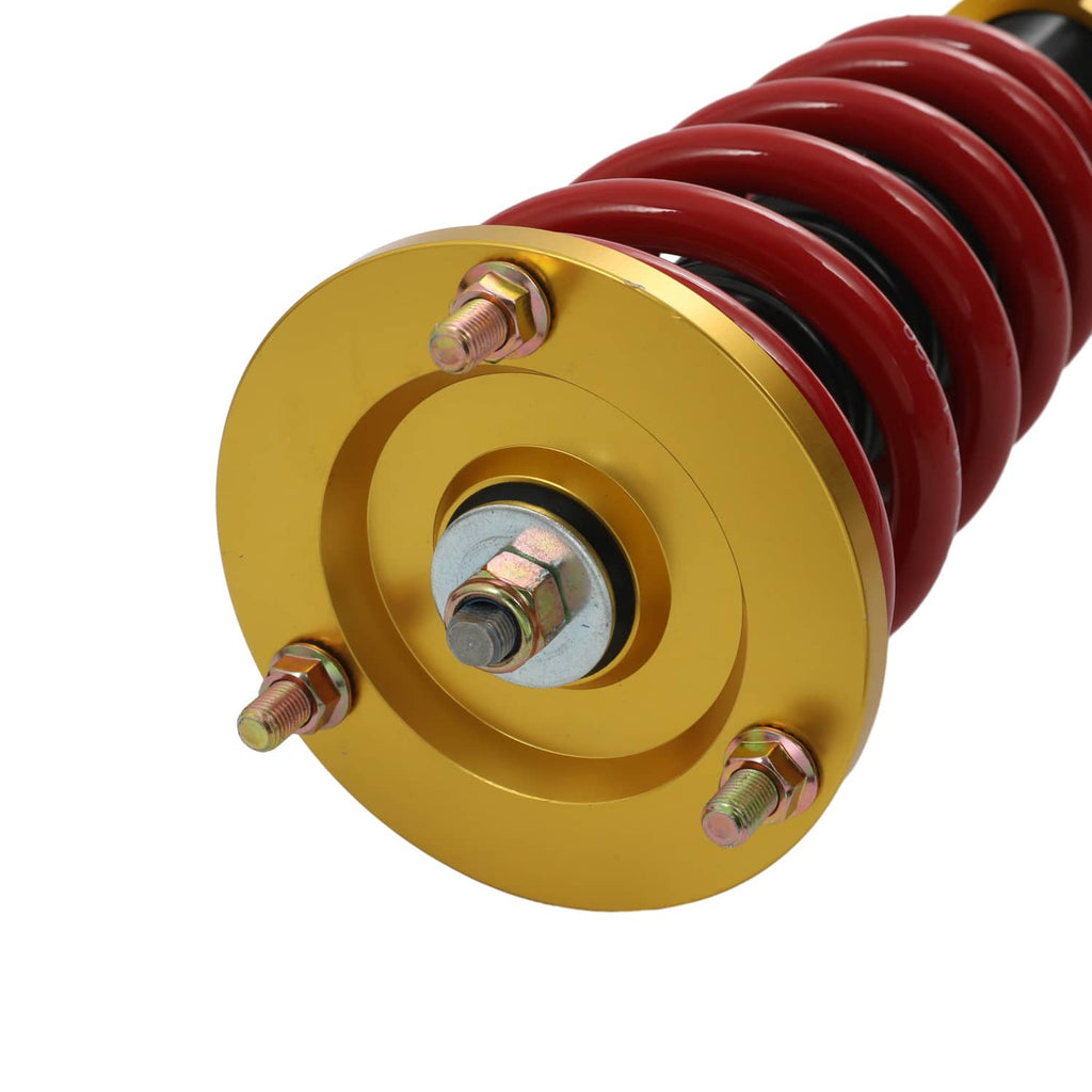 Close-up of coilover strut top mount: gold plate, red spring, and steel bolts