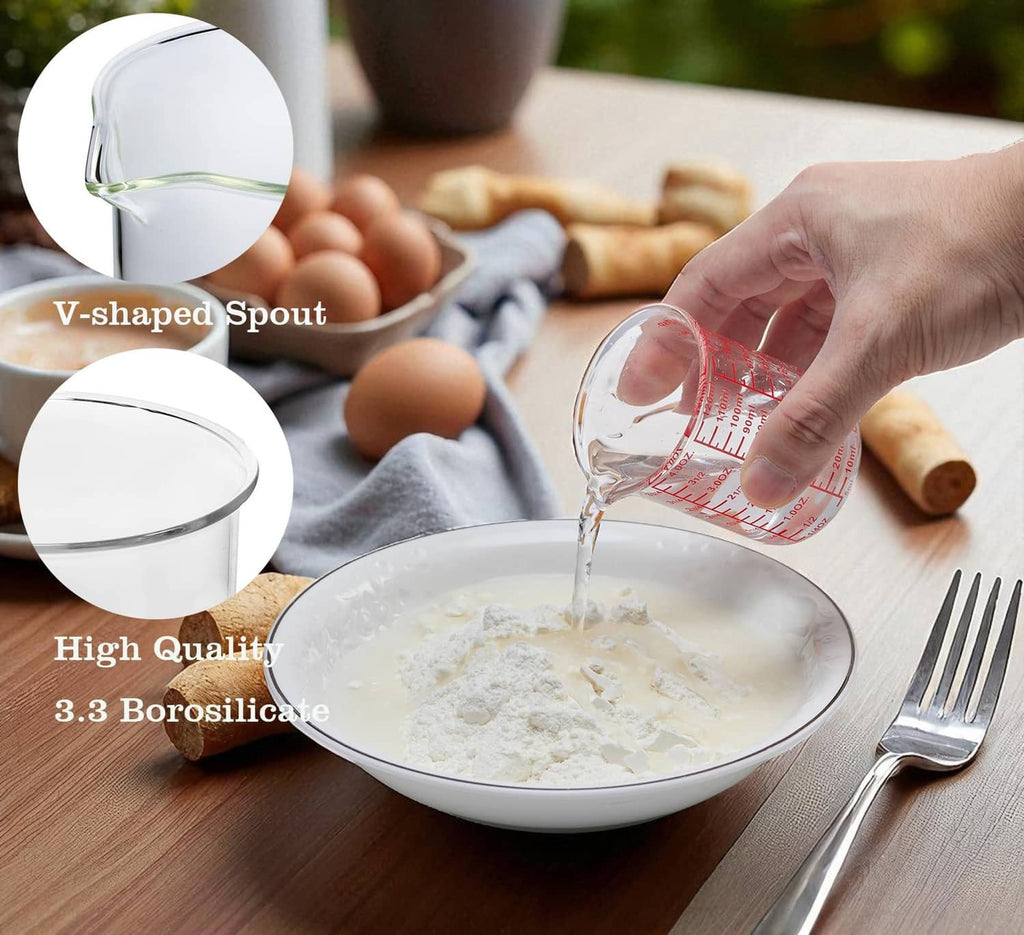 Clear V-shaped glass measuring cup with red scale markings and pour spout, 120 mL.