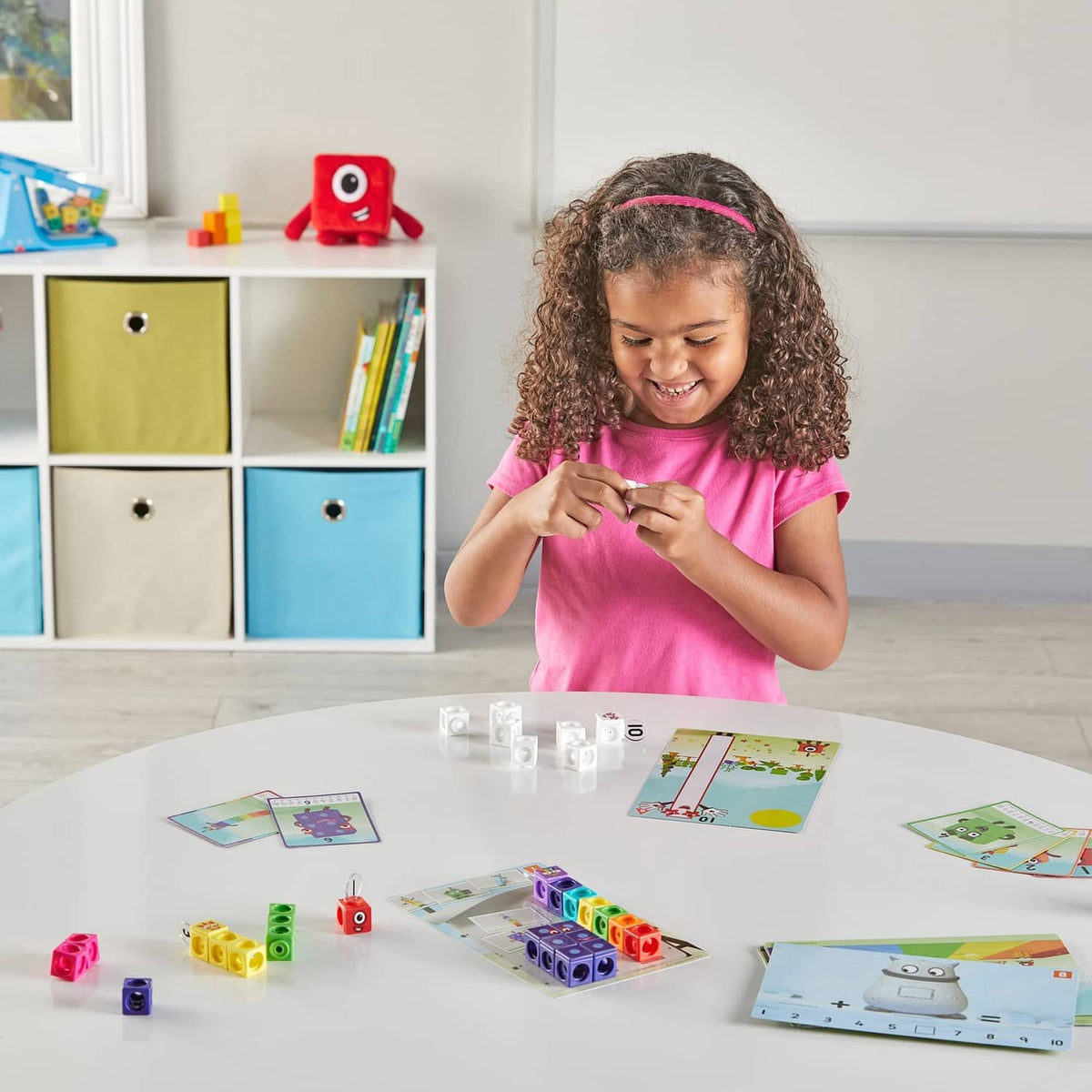 Child placing Numberblocks cubes while using matching activity cards on a table