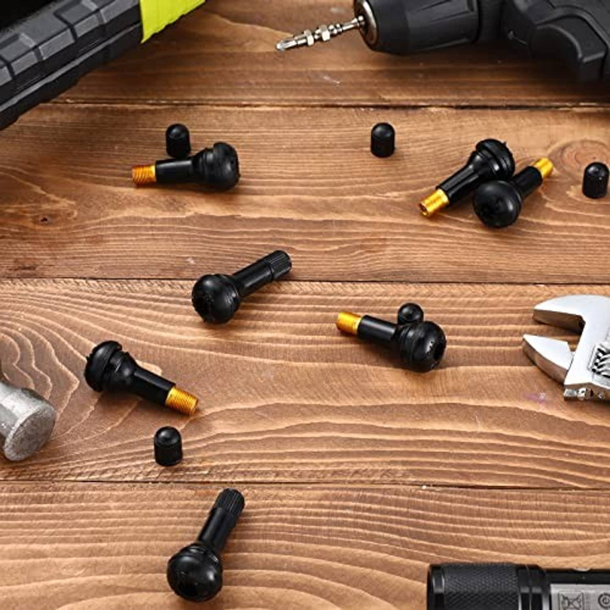 Assorted black tubeless snap-in valve stems with gold threaded cores on wood