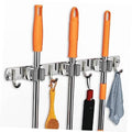 Chrome wall-mount broom organizer with three racks and four curved hooks, holding orange handles