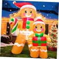 Outdoor inflatable gingerbread figures, one holding candy cane and one holding a green gift