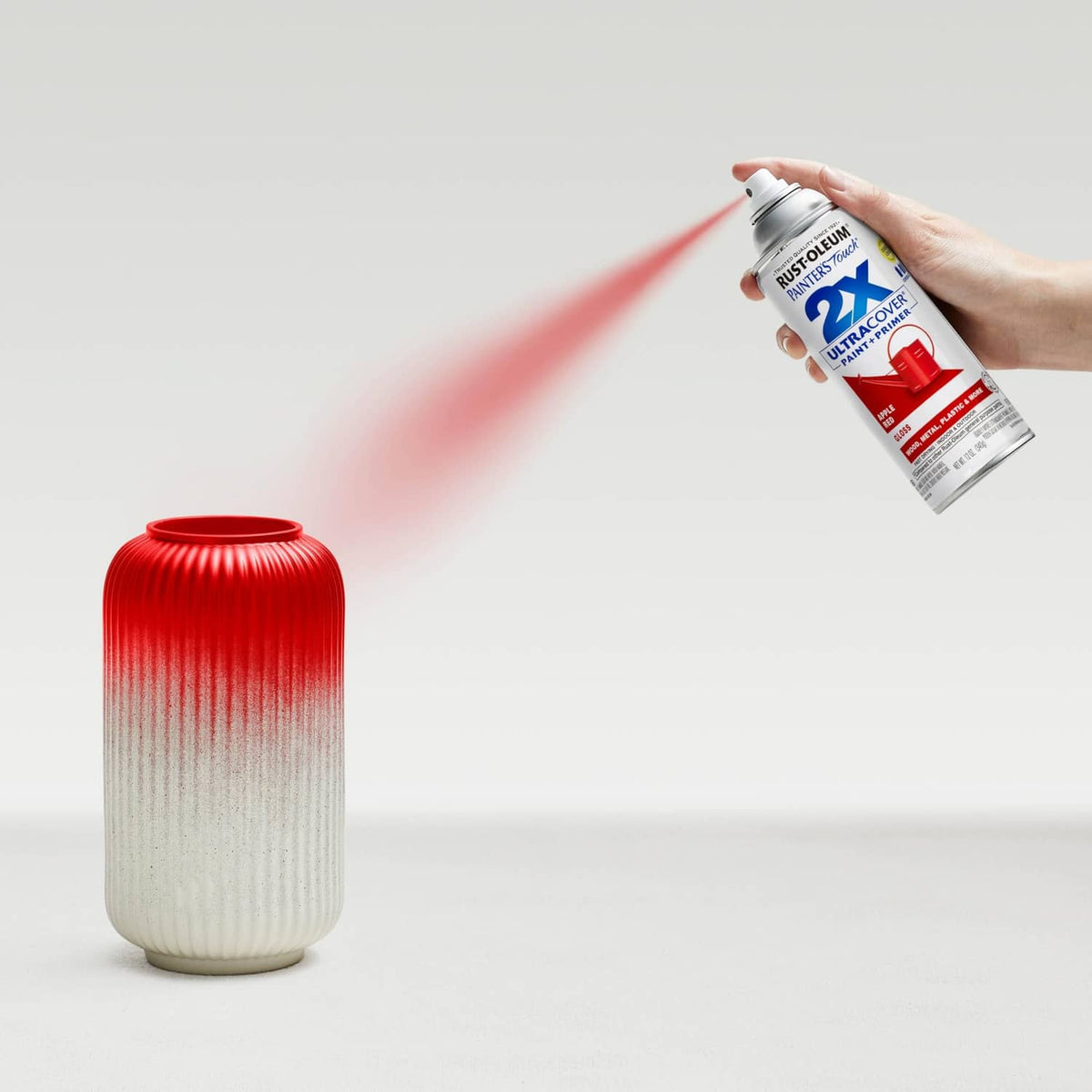 Spray paint can misting a ribbed vase, red gradient spray finish.