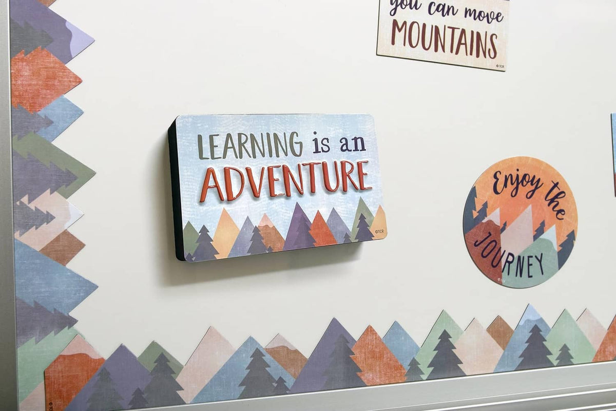 Magnetic whiteboard with “Learning is an Adventure” text and colorful mountain scene