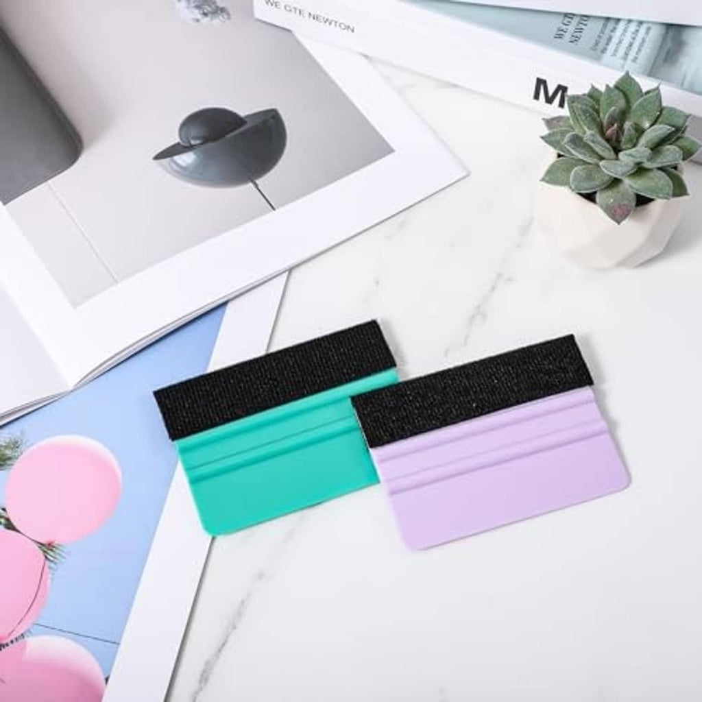 Two vinyl felt squeegees on paper: teal and purple plastic with black felt edges