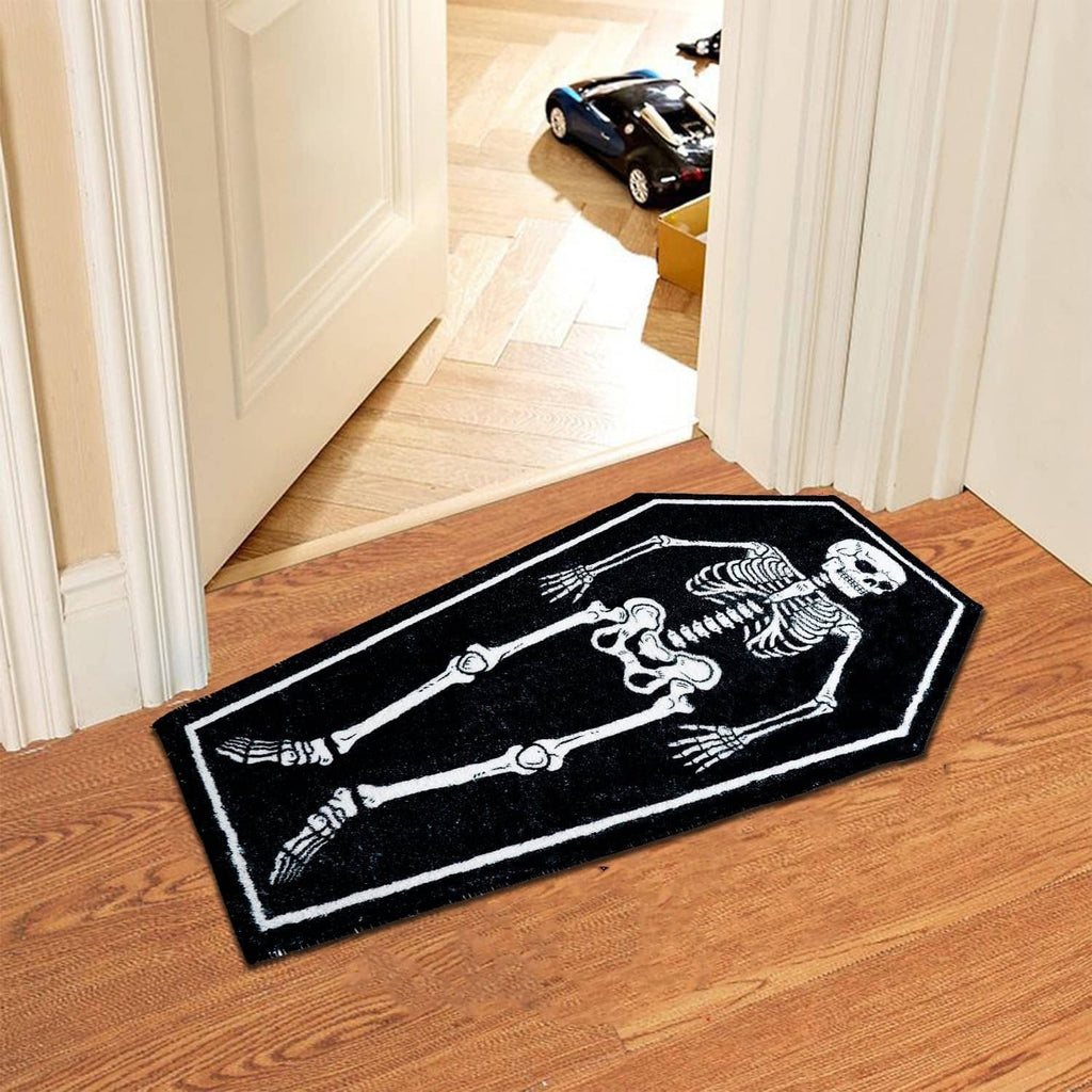 Rectangular black bath mat with white skeleton bones graphic on hardwood floor