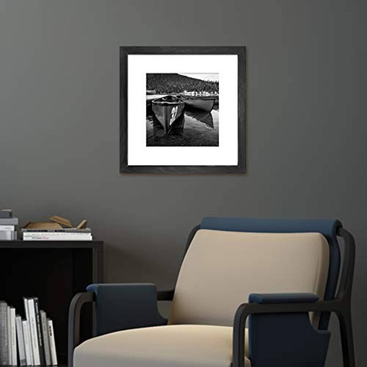 Black 12x12 picture frame with white mat on a wall above a chair.