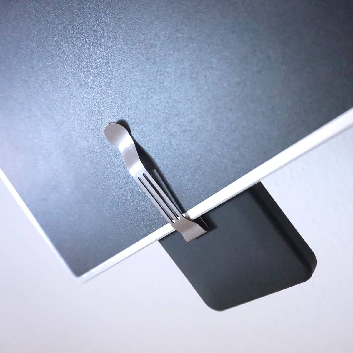 Silver pocket clip mounted on a corner of a dark device