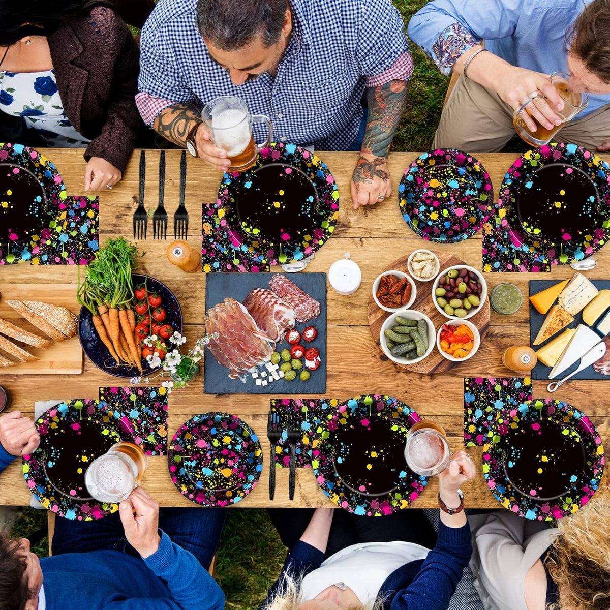 Neon splatter glow plates and napkins on a shared outdoor table for a party