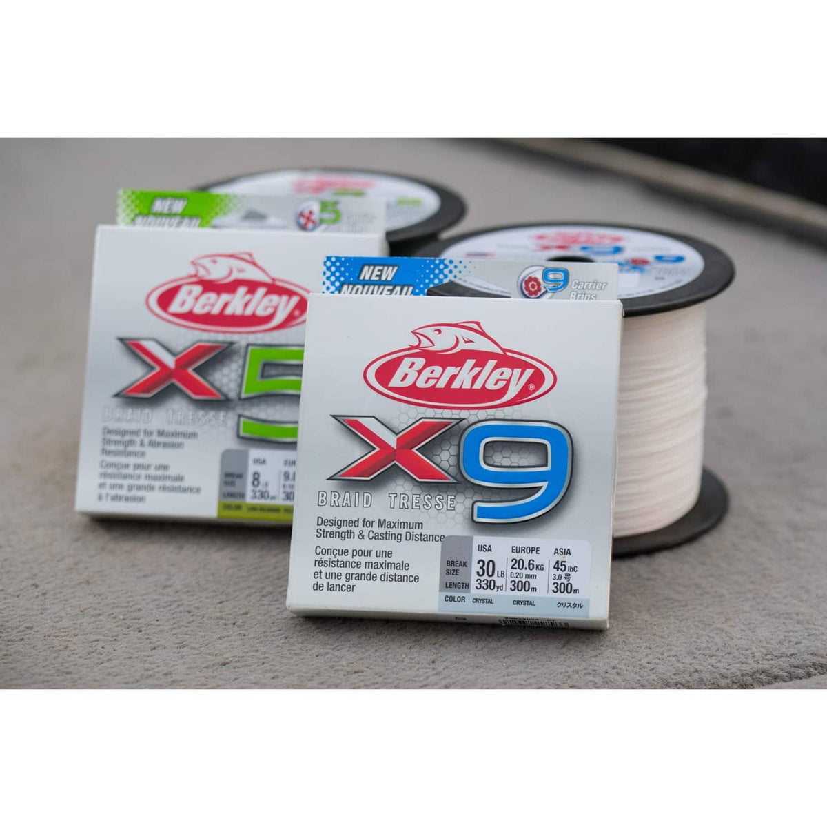 Berkley X5 and X9 braided fishing line boxes with white line spool on surface