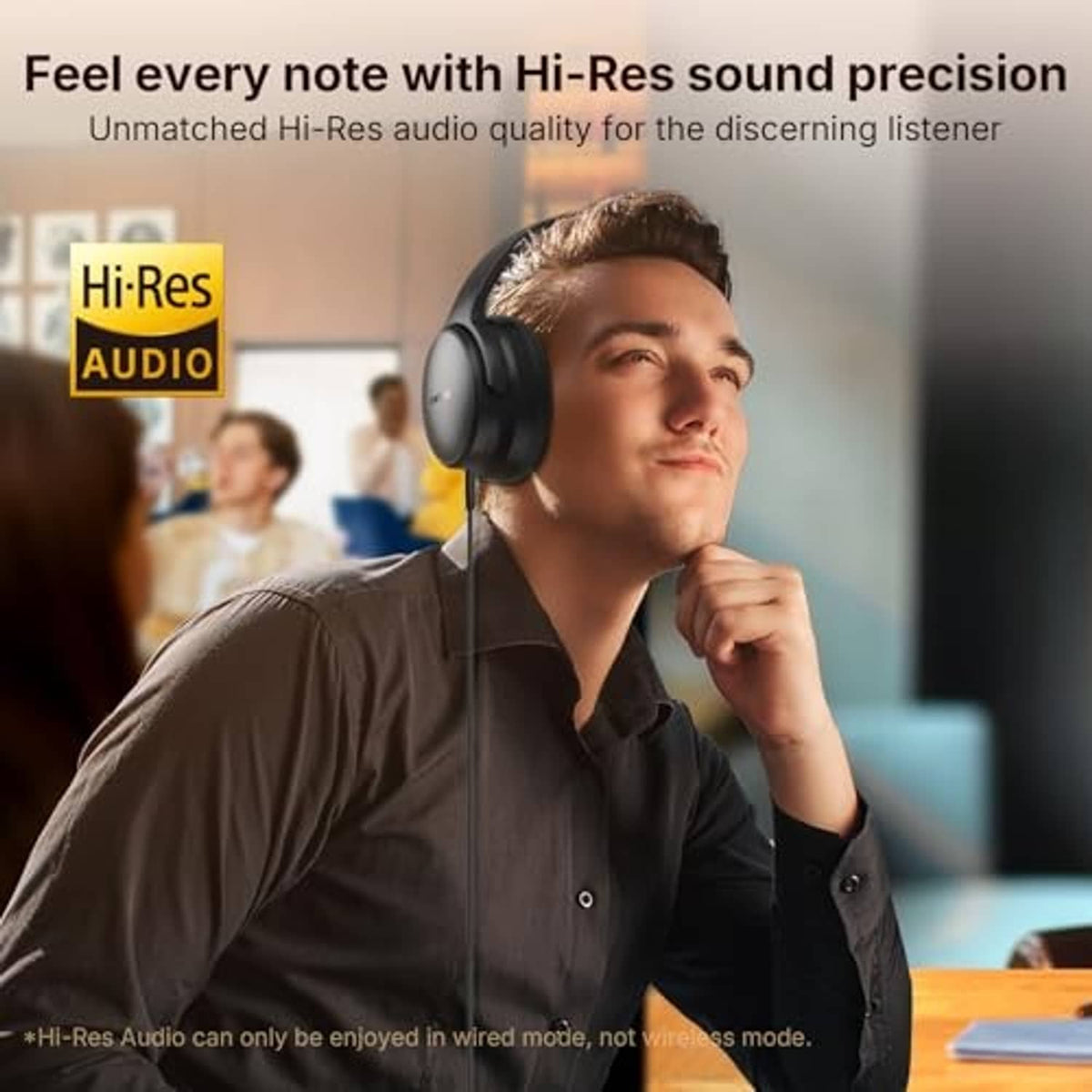 Black over-ear headphones worn by a seated person with a relaxed smile.