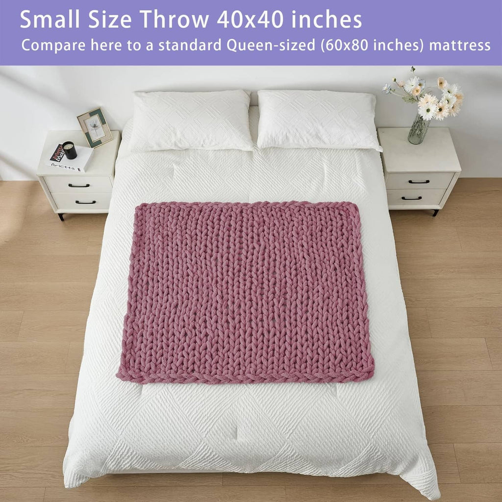Small throw blanket, burnt rose chunky knit, folded on white bed