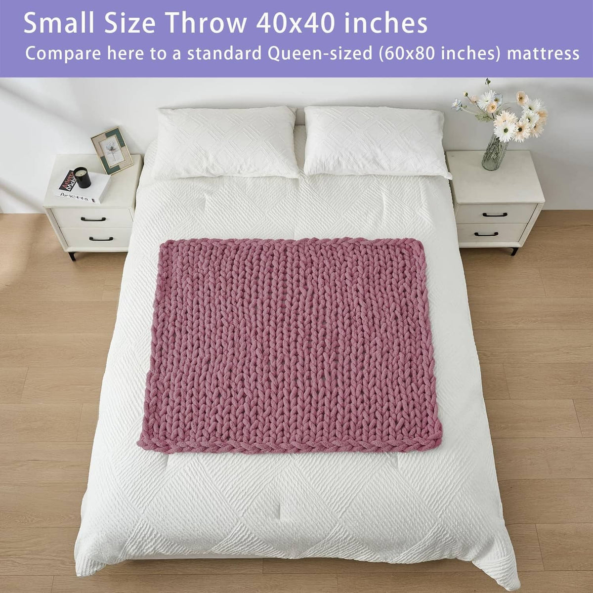 Small throw blanket, burnt rose chunky knit, folded on white bed