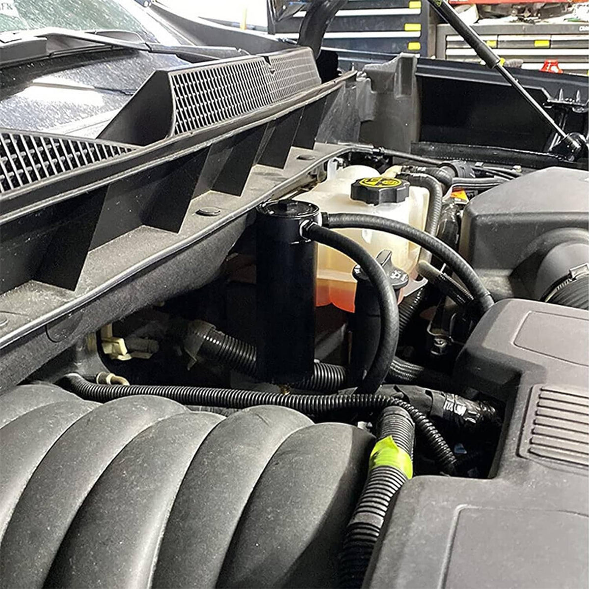 Oil catch can installed under engine bay with attached hoses and compact black reservoir