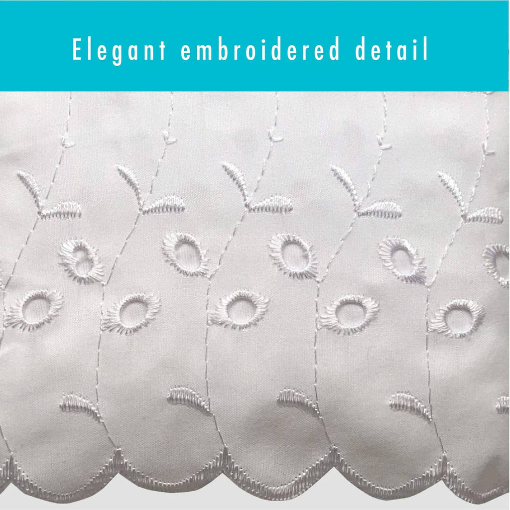 White eyelet embroidery close-up with scalloped cutwork and stitched medallion shapes