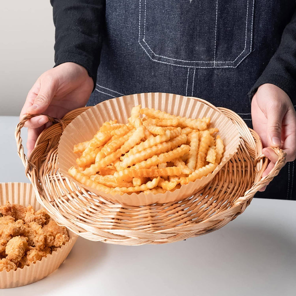 Round kraft paper air fryer liner holding fried food in a woven basket